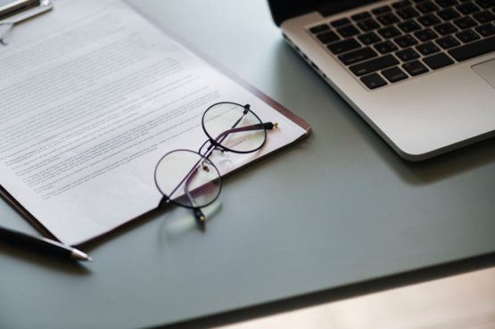 glasses on top of a clipboard with paperwork