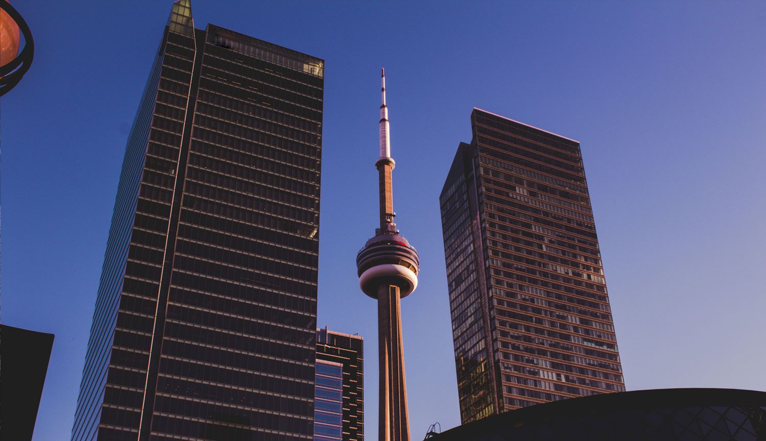 the CN tower between two high rise office buildings